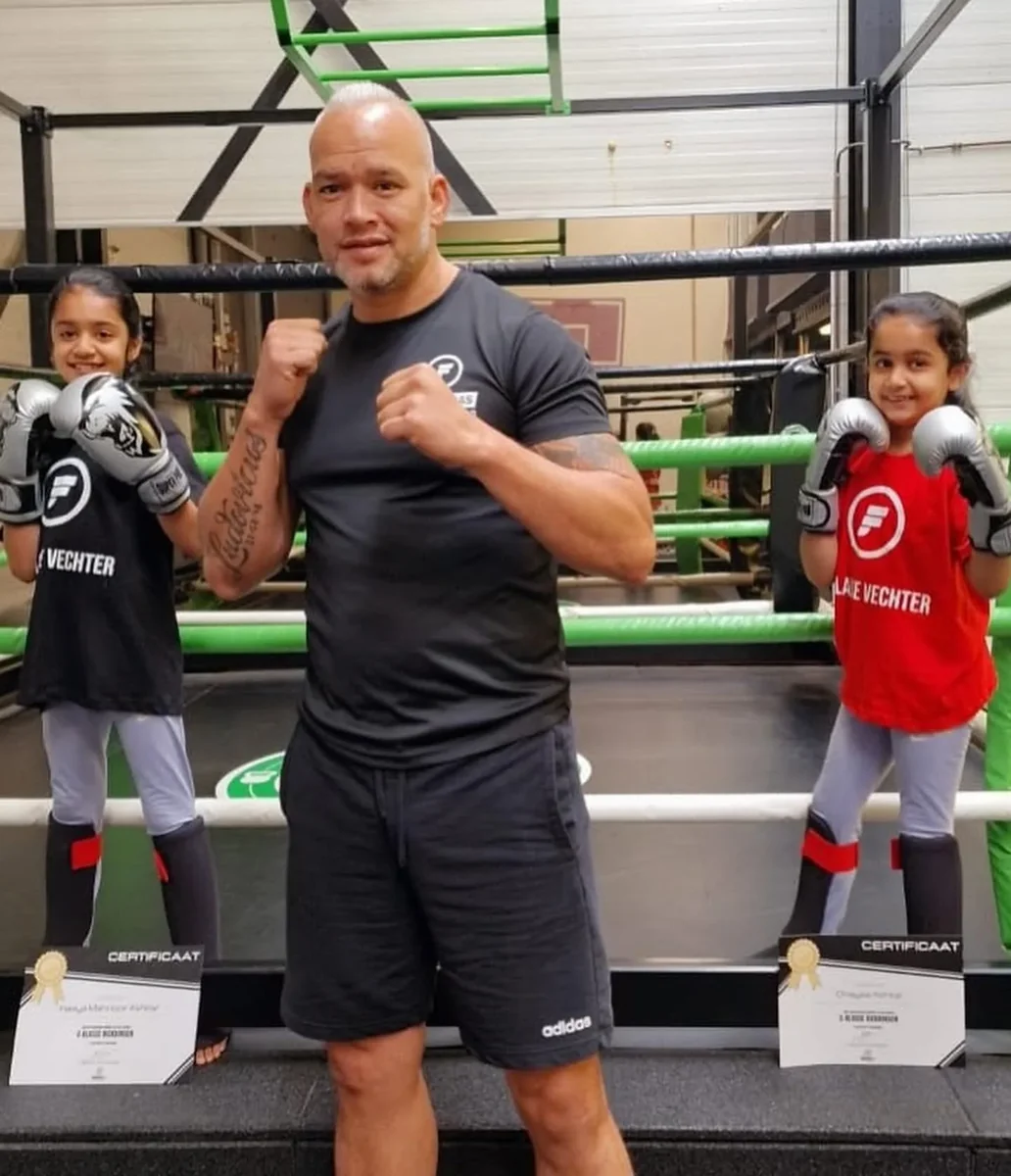 Bas met twee jonge leerlingen en hun certificaten na de kickboksles